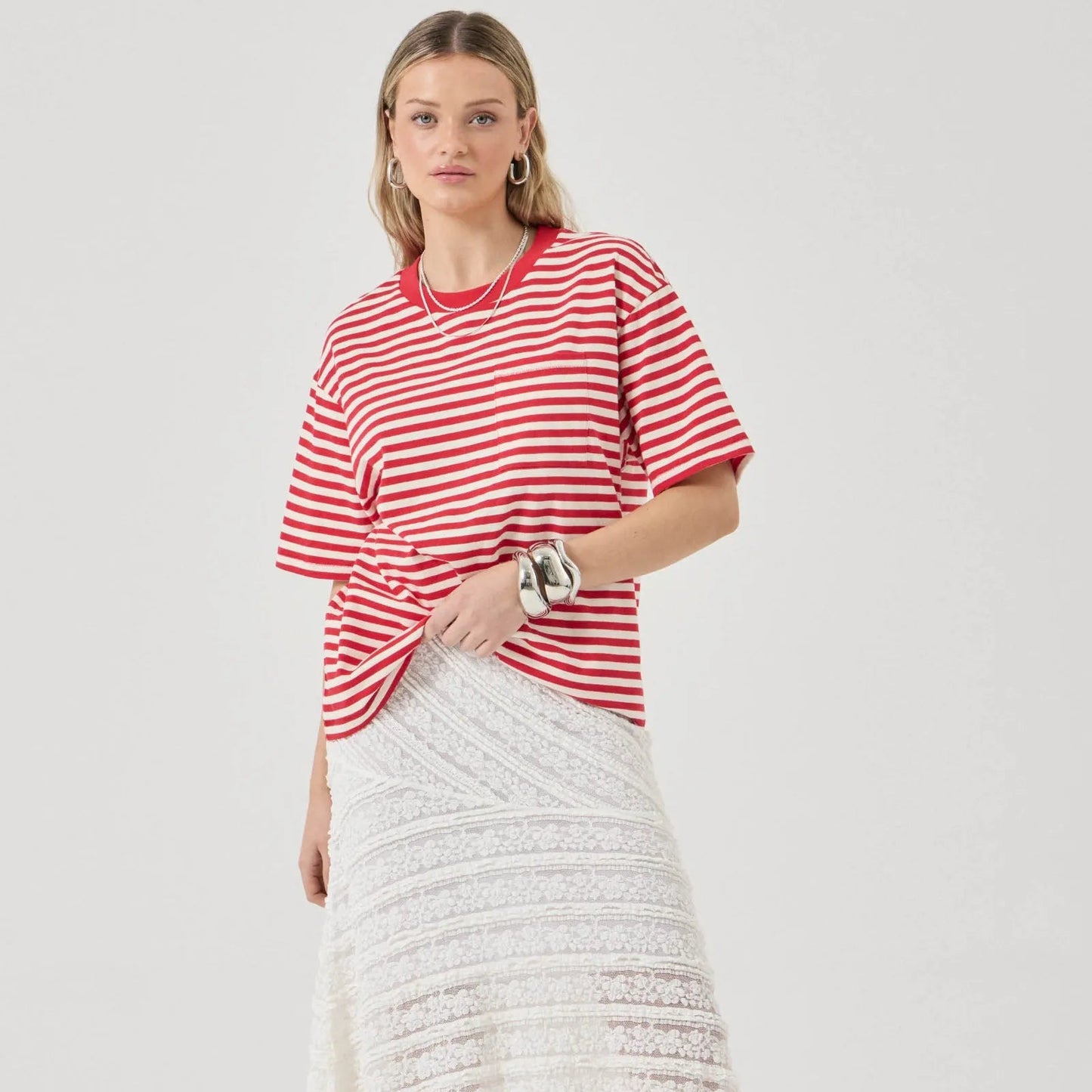 Woman wearing a red and white striped shirt and white skirt on a white background
