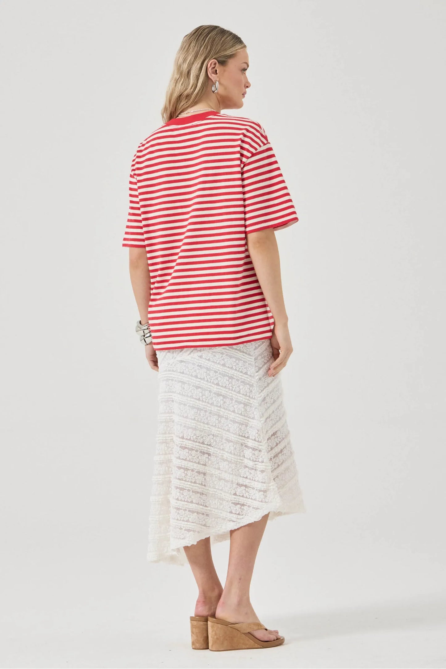Woman wearing a red and white striped shirt and a light-colored skirt on a white background