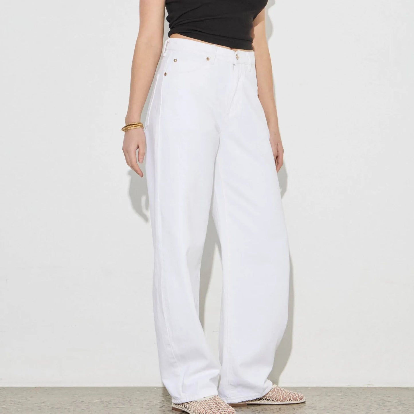 Woman wearing a black t-shirt and white pants against a plain background