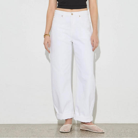 Woman wearing a black crop top and white pants against a plain background